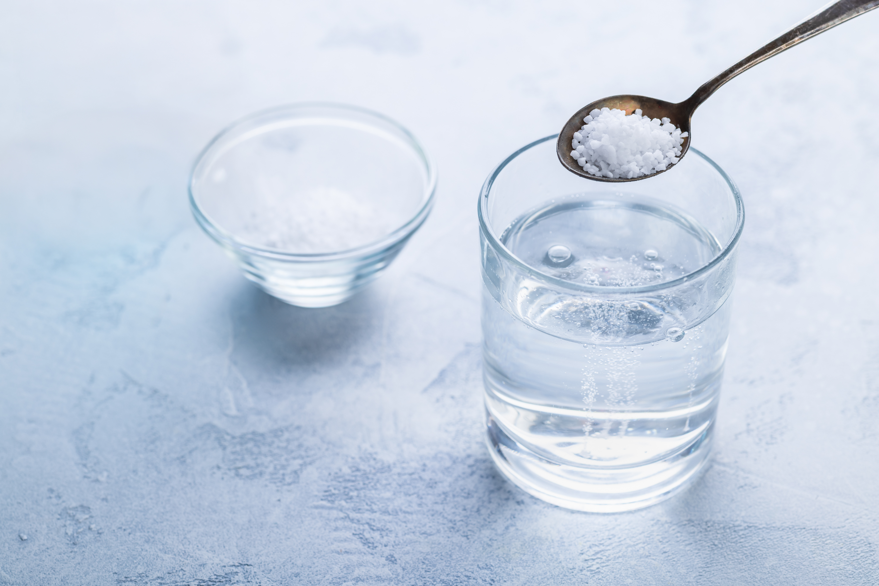 A glass of water with an electrolyte powder stick pack beside it