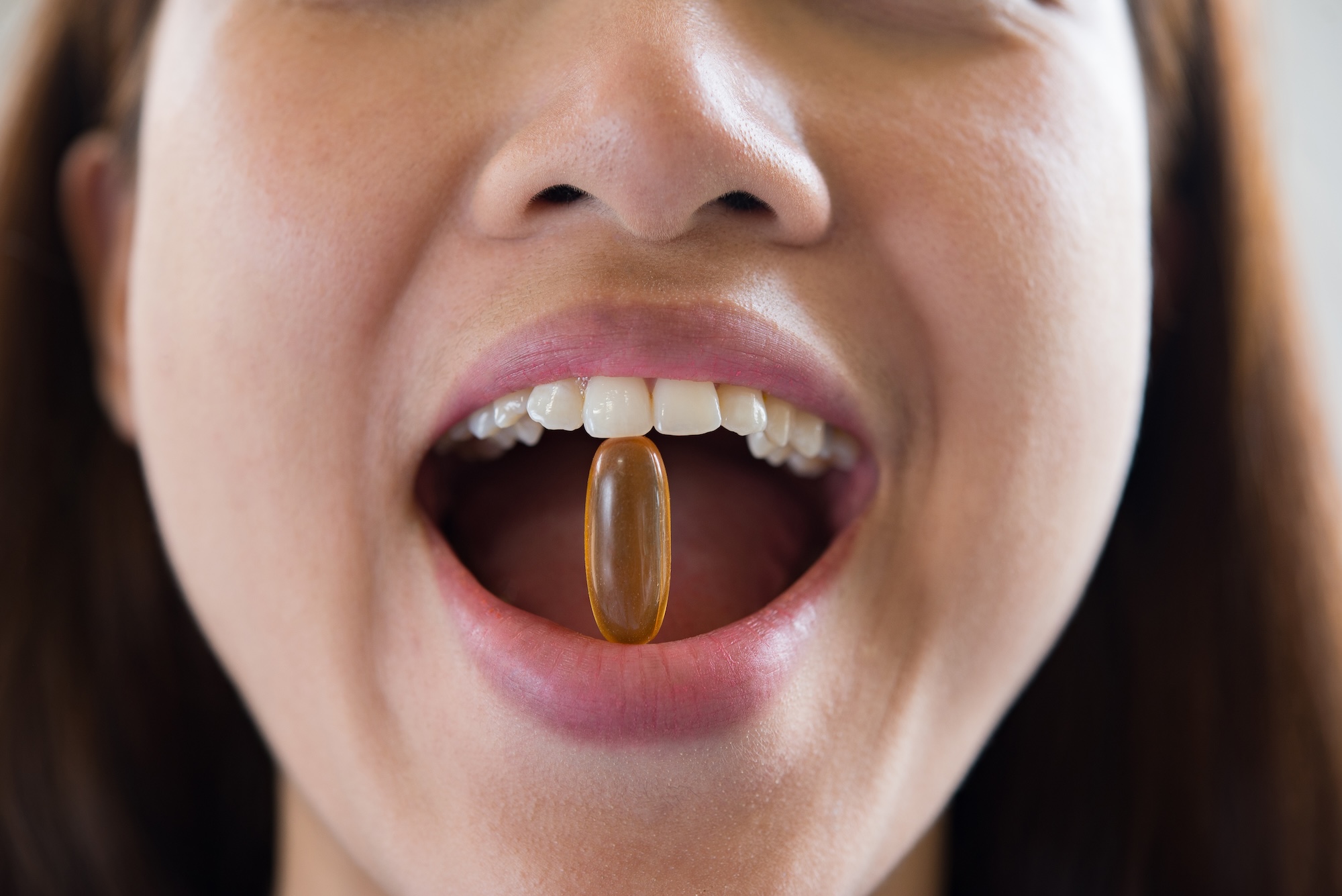 Unbranded hyaluronic acid capsules and gummies beside a glass of water