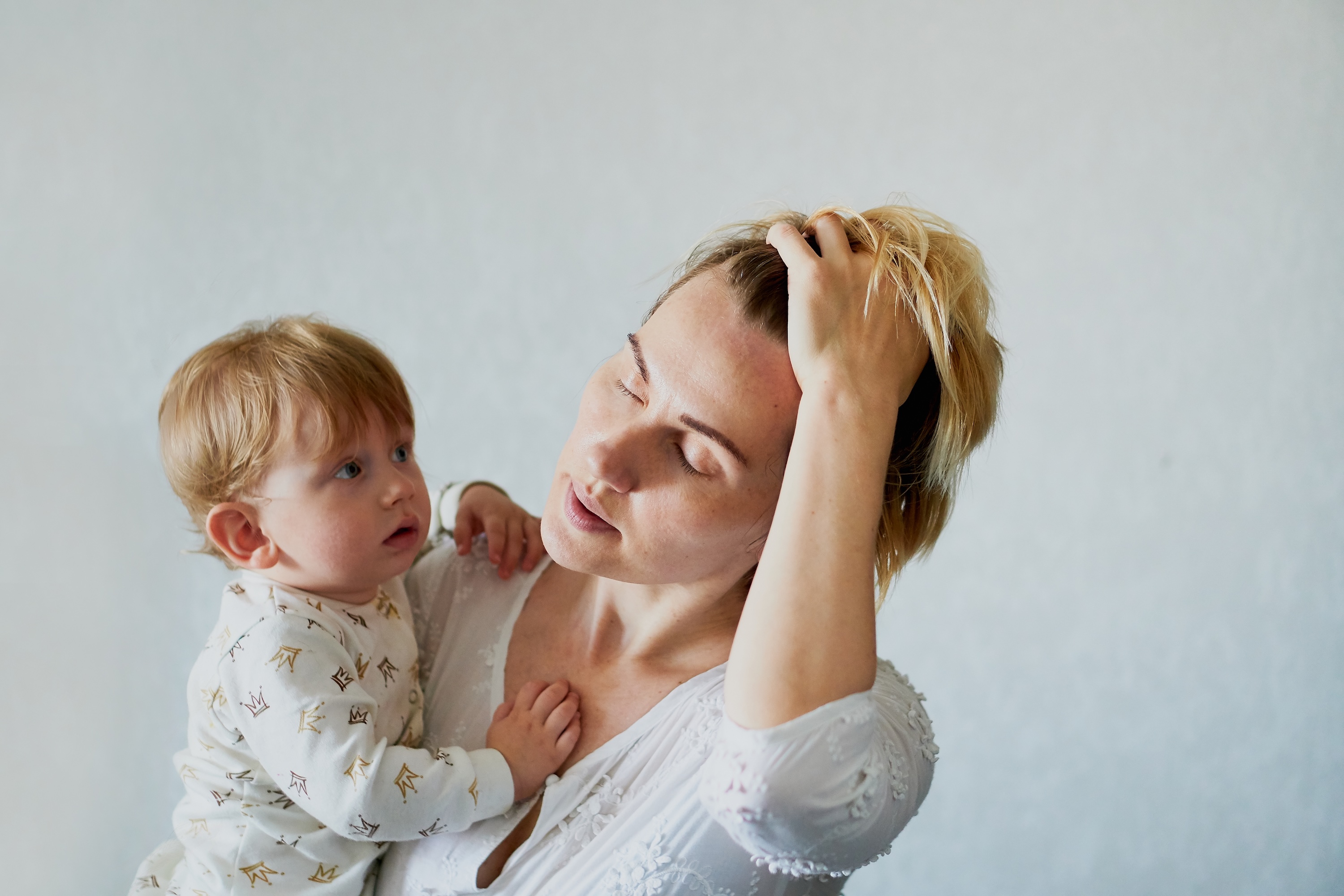 Woman examining hair shedding in a hairbrush postpartum