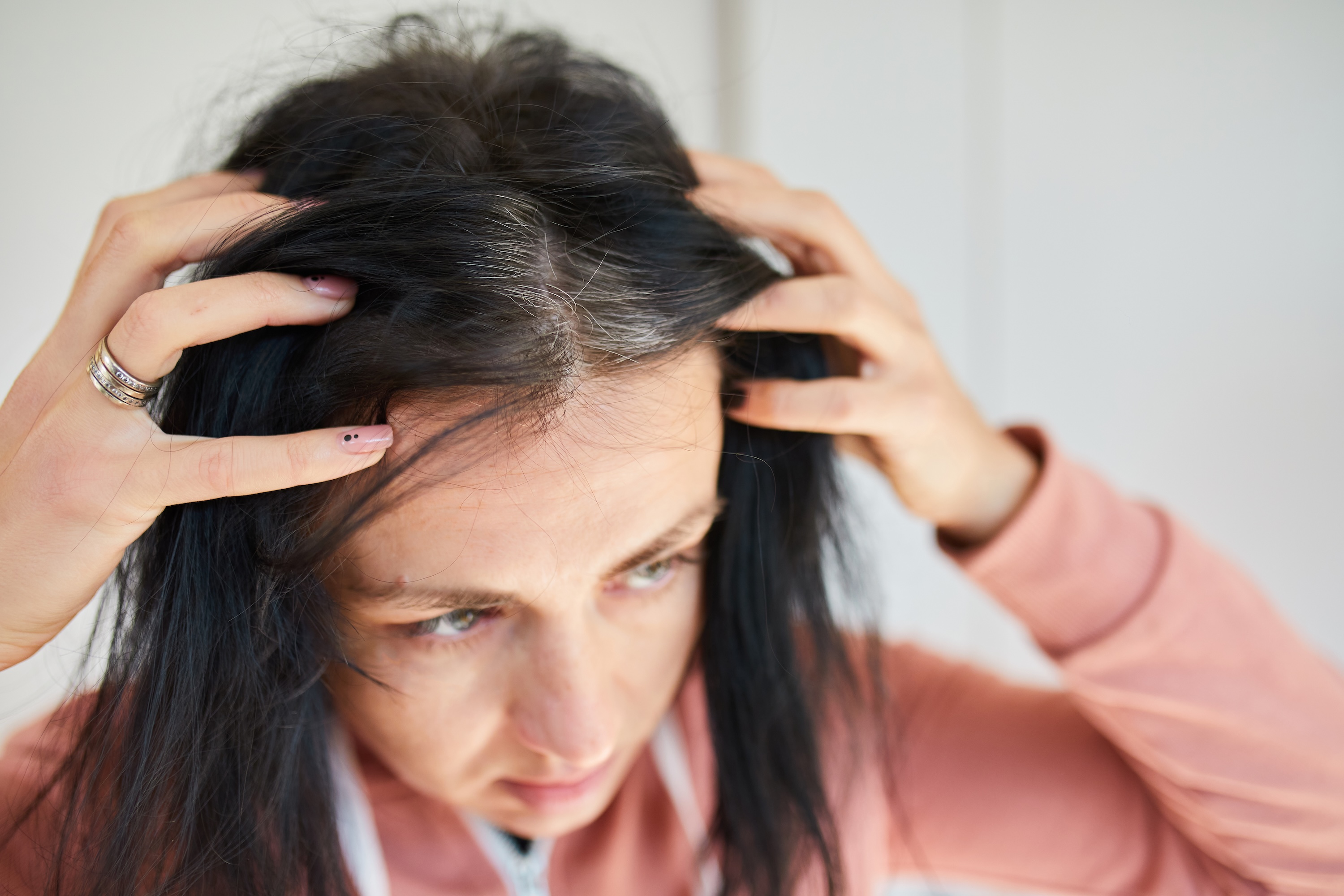 Woman examining hair loss, illustrating the compounding stress of perimenopausal hair changes